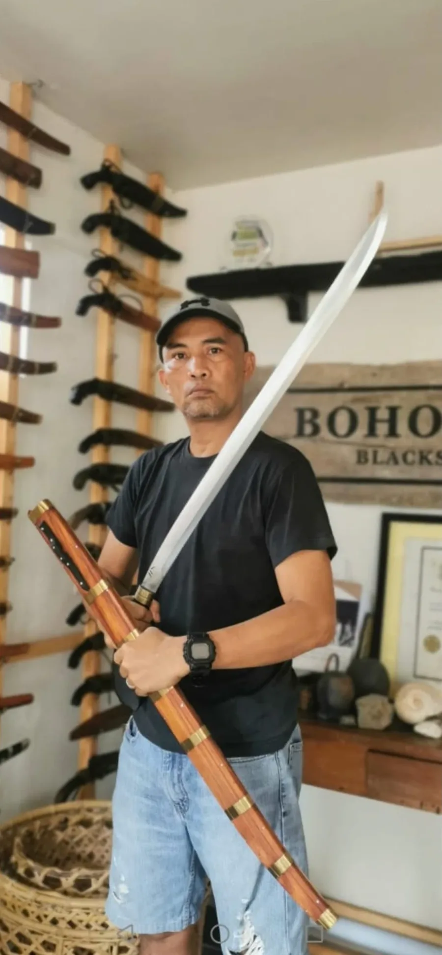 Cid Cempron, proprietor of Bohol Blades, holding a long blade with its brass-banded rosewood scabbard