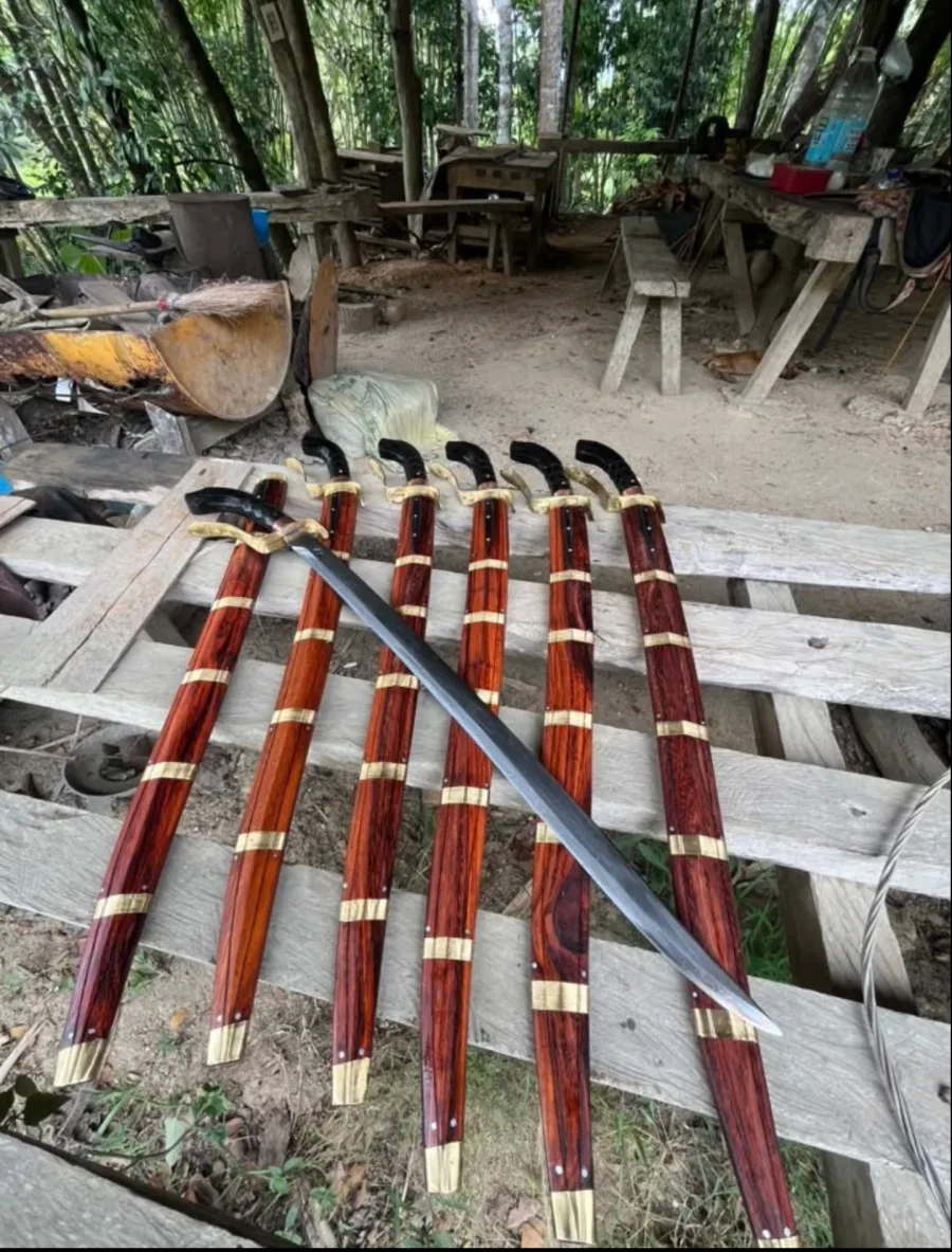 Six long blades with brass-banded rosewood scabbards laid out at the forge